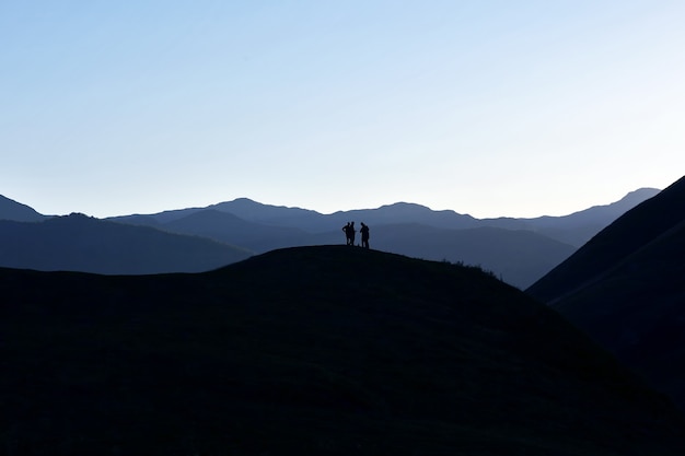 Silhouette of people standing on the hillside
