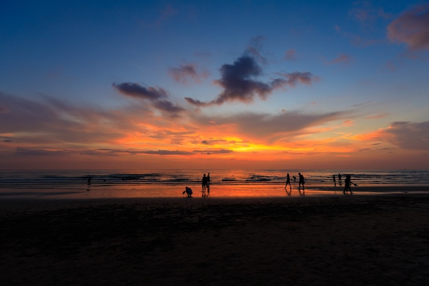 Силуэт людей на закате пляж с оранжевым небом с красивой голубой