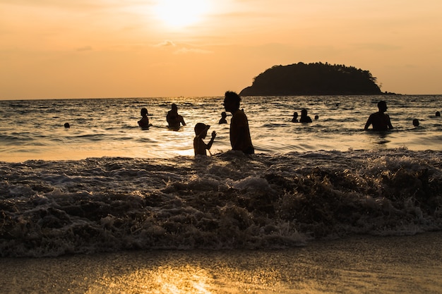 シルエットの人々波海のビーチの夕日