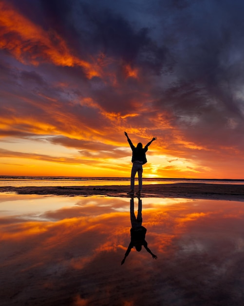 Photo silhouette person against background beautiful sunset sky on ocean reflection rays sun in water