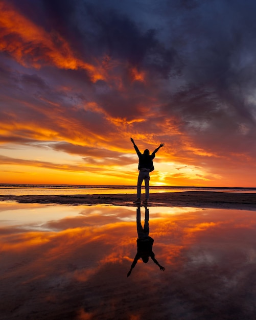 Фото Силуэт человека на фоне красивого закатного неба в океане отражение лучей солнца в воде