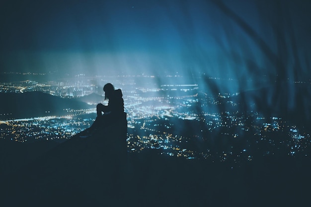 夜の照らされた都市風景に照らされた人のシルエット