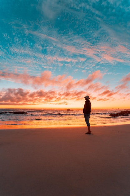 Silhouette of a person on the beach contemplating a beautiful sunset on the horizon