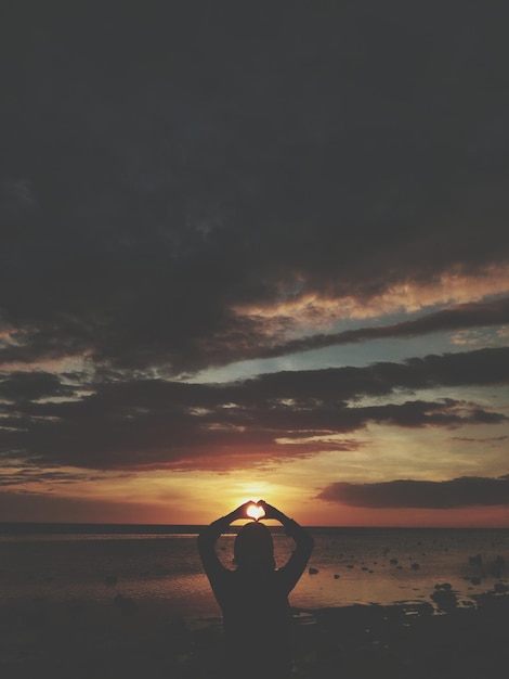 Photo silhouette person by sea against sky during sunset