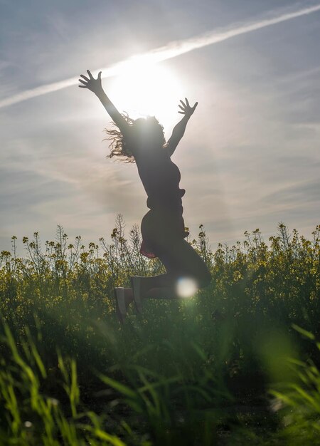 Foto silhouette di una persona che salta sul campo contro il cielo