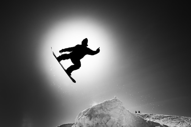 Silhouette person jumping on rock against sky