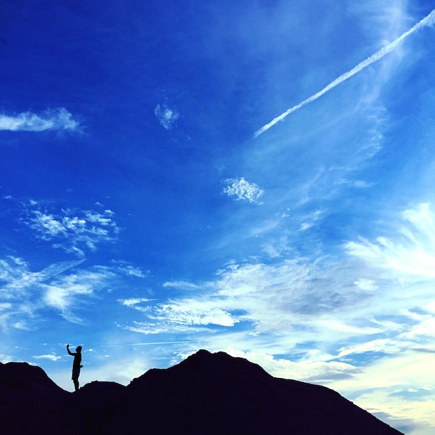 天空を背景に山のシルエットの人