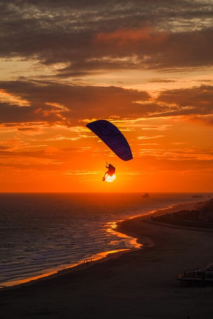 Foto silhouette di una persona in parapendio al tramonto zoutelande zeeland paesi bassi