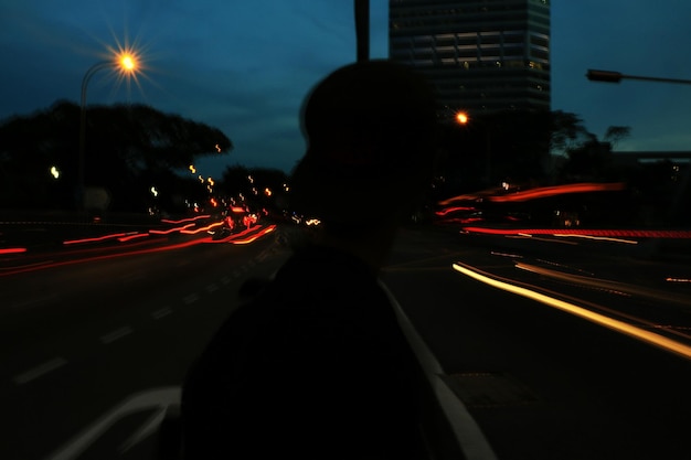 Foto silhouette di una persona sulla strada con tracce di luce di notte