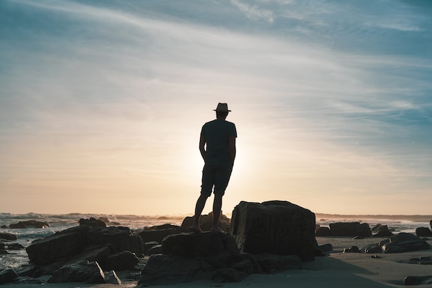 silhouette of a person on the rocky beach at sunset