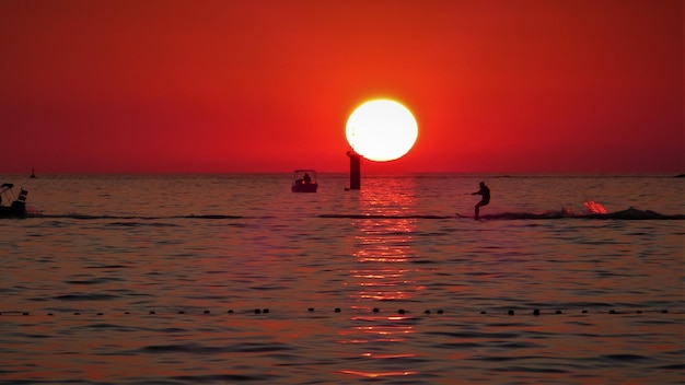 Foto silhouette di una persona in mare contro il cielo durante il tramonto