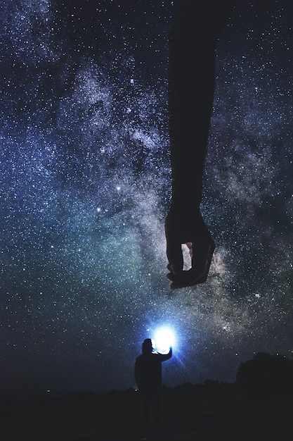 夜に星の場に立っているシルエットの人