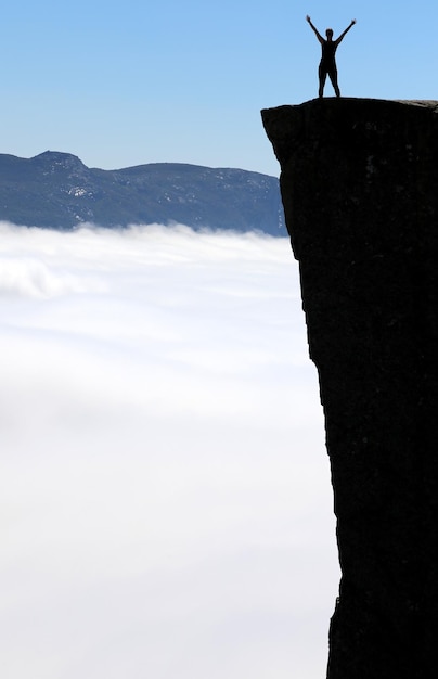 Photo silhouette person standing by cloudscape on cliff