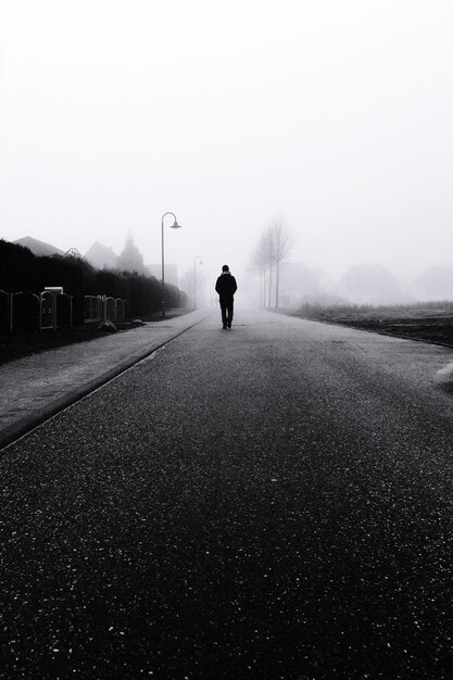 Photo silhouette person walking on road