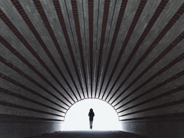 Foto silhouette di una persona che cammina nel tunnel
