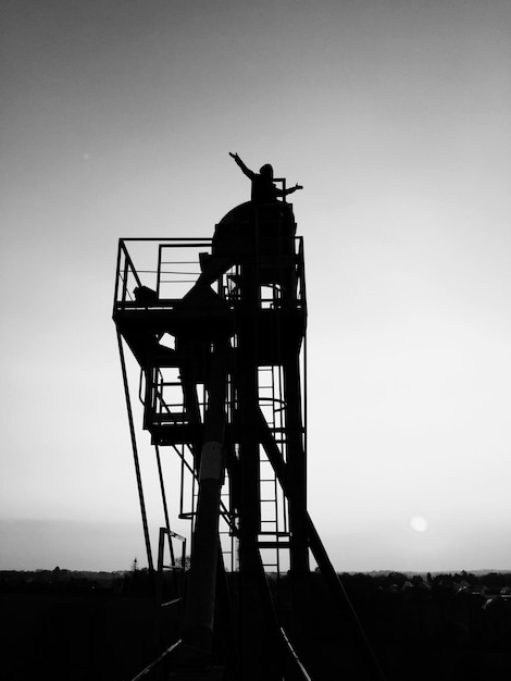 Photo silhouette person with arms outstretched standing on observation point against clear sky