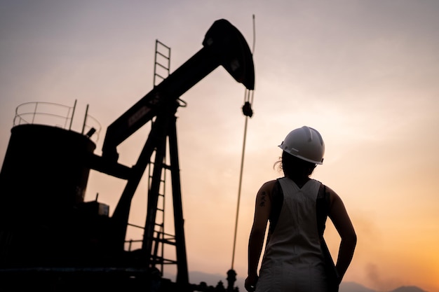 Silhouette Petrochemical engineering asian woman with safety helmet standing in oil refinery structure petrochemical industry