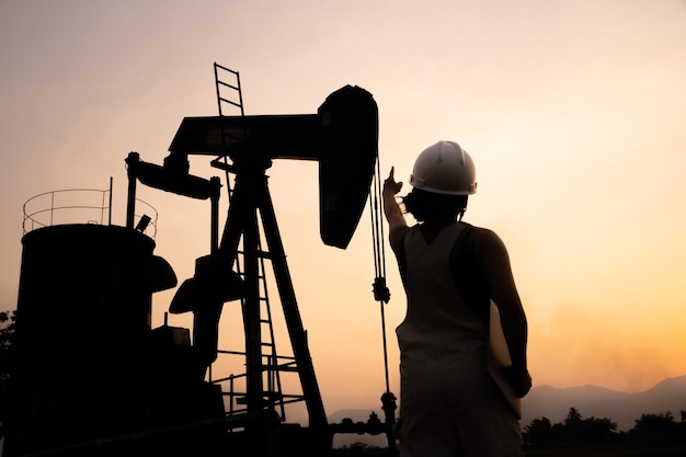 Silhouette Petrochemical engineering asian woman with safety helmet standing in oil refinery structure petrochemical industry