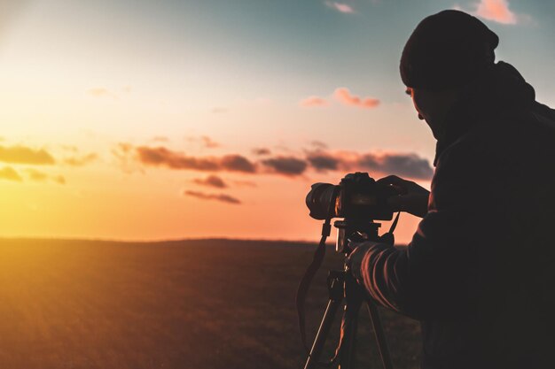 Silhouette of a photographer on a sunset background with a tripod