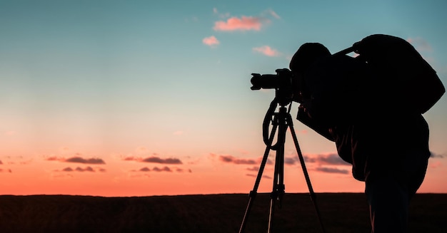 Silhouette of a photographer on a sunset background with a tripod