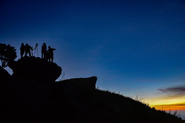 Photo silhouette of photographer on the top of mountain at sunrise at phu chi fa thailand