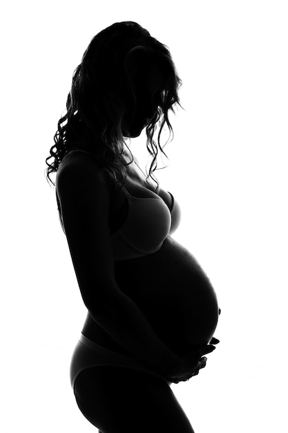 Силуэт беременной женщины на белом фоне