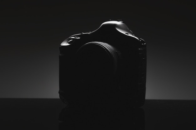 The silhouette of a professional slr camera on a black\
background presentation of a new product