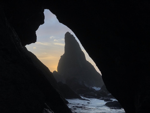 Photo silhouette rock formation on beach against sky during sunset