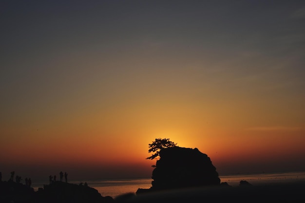 Foto silhouette di rocce sul mare contro il cielo durante il tramonto
