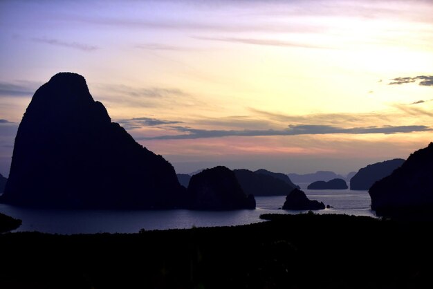 Silhouette rocks by sea against sky during sunset