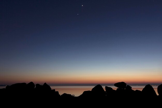 Foto silhouette di rocce e mare contro il cielo al crepuscolo