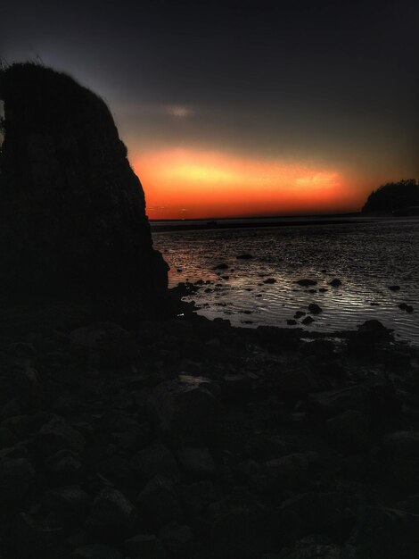 Foto silhouette di rocce in mare contro il cielo al tramonto