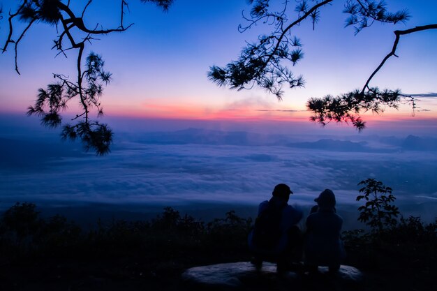  silhouette Romantic couple and sit and watch the sunrise on the mountain.