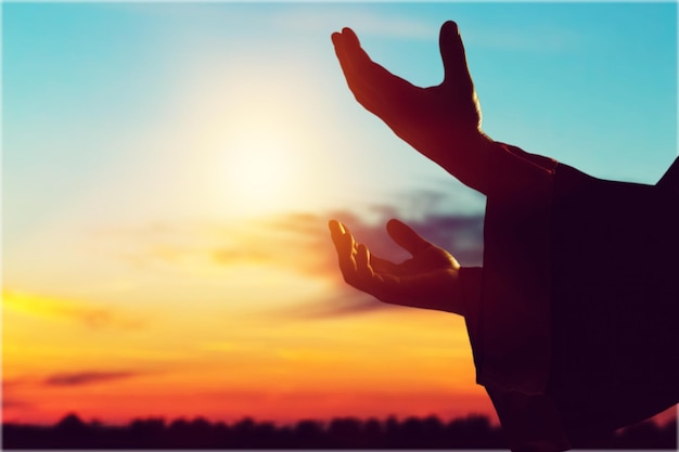 Silhouette rosary against cross in hand