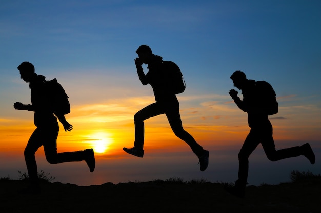 Siluetta dell'uomo corrente contro il cielo variopinto. siluetta dell'uomo corrente sul fondo ardente di tramonto