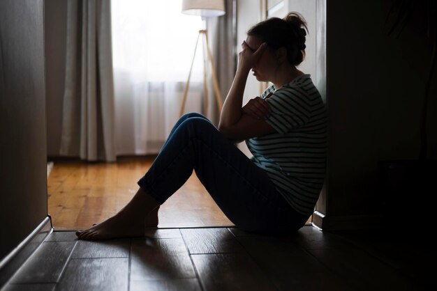 집 의 바닥 에 앉아 있는 슬프고 우울 한 여자 의 실루