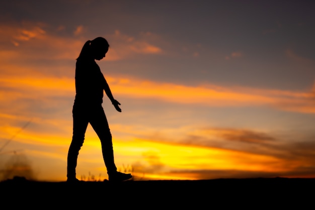 Silhouette of sad and depressed women walking at walkway of park with sunset