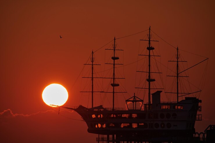 Photo オレンジ色の空を背景に海に浮かぶシルエットの帆船