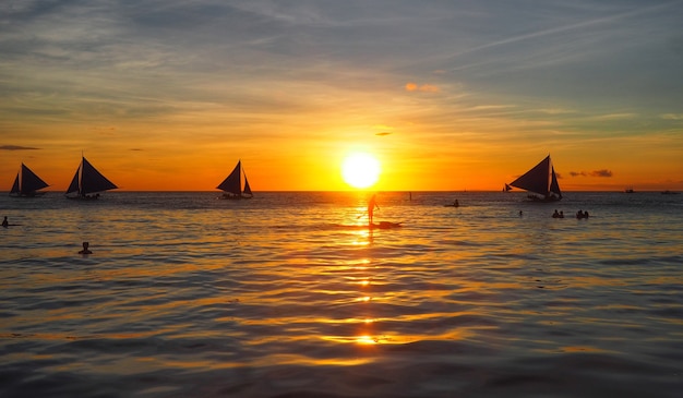 Sagoma scenario del tramonto nel mare e il viaggiatore sulla barca a vela boracay island