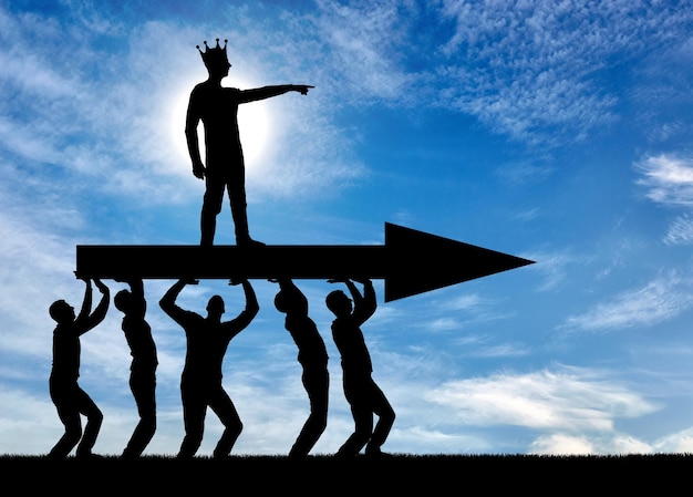 The silhouette of a selfish man with a crown on his head indicates to people who carry him, where to move. The concept of selfish behavior towards other people