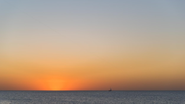 Foto silhouette di nave sull'orizzonte del mare e un aereo che vola nel cielo sopra di esso durante la bella