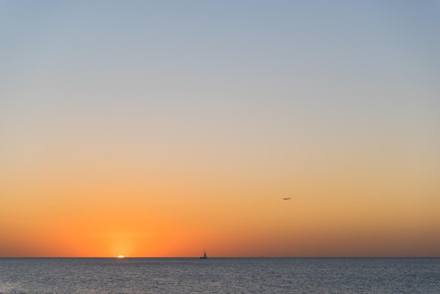 Foto silhouette di nave sull'orizzonte del mare e un aereo che vola nel cielo sopra di esso durante la bella