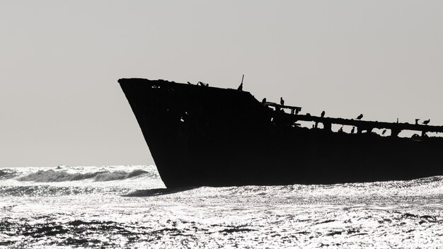 Silhouette of ship wreck on beach against clear sky