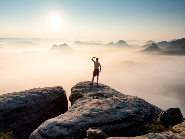 Foto silhouette di un turista senza camicia e un bellissimo paesaggio collinare nebbioso come sfondo