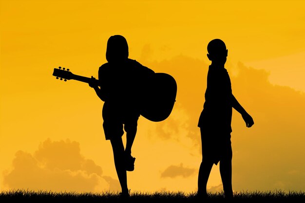 Silhouette siblings with guitar on field against sky during sunset