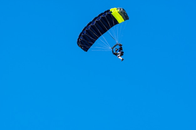 Silhouette of skydiver flying in blue clear sky.