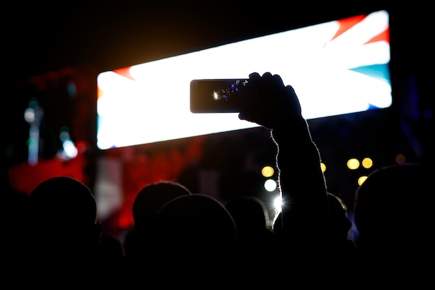 Silhouette of smartphone in hands of fan during music show