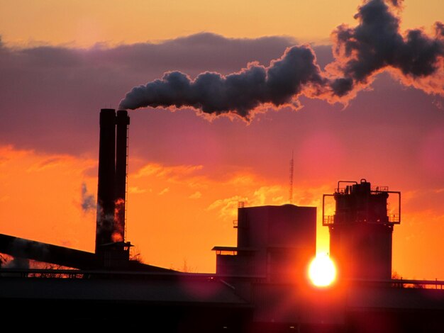 Photo silhouette smoke stacks against sky during sunset