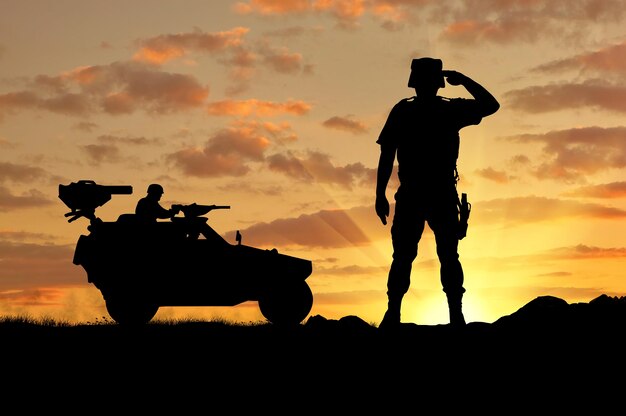 Silhouette di un soldato e un veicolo da combattimento humvee al tramonto