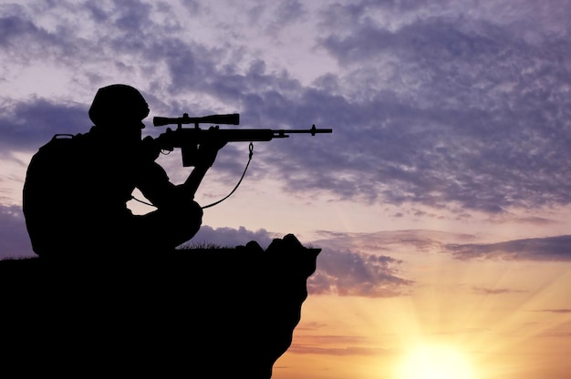 Silhouette of a soldier sniper on top at sunset